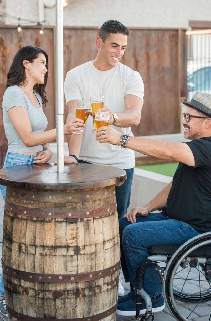 Friends sharing a drink, and toasting. One of the party is in a wheelchair. 